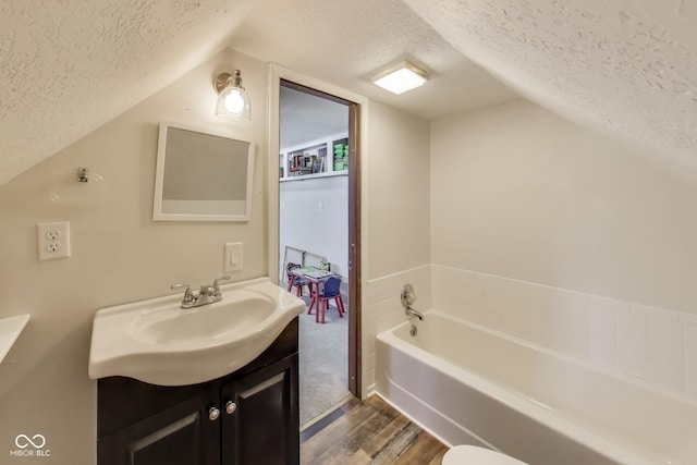 307 E Walnut St, Lebanon, IN 46052 - bathroom with a textured ceiling, vanity, wood finished floors, a garden tub, and vaulted ceiling