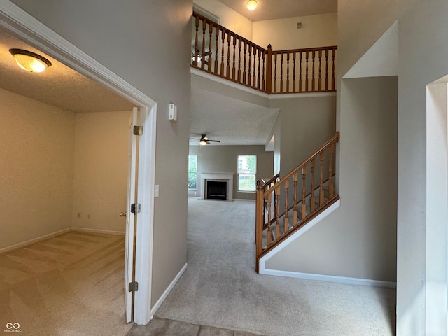 14520 Brackney Ln, Carmel, IN 46032 - staircase with carpet, a fireplace, a ceiling fan, and a high ceiling