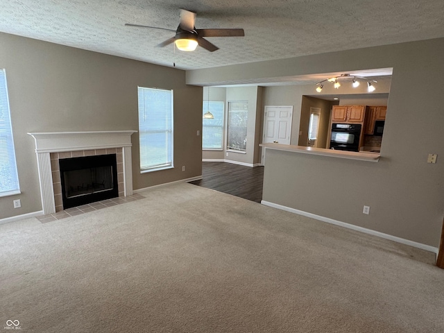 14520 Brackney Ln, Carmel, IN 46032 - unfurnished living room with carpet flooring, a tile fireplace, ceiling fan, and a textured ceiling