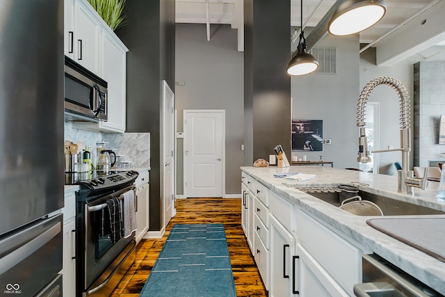 624 E Walnut St Unit 26, Indianapolis, IN 46204 - kitchen with appliances with stainless steel finishes, a high ceiling, dark wood-style floors, white cabinets, and backsplash