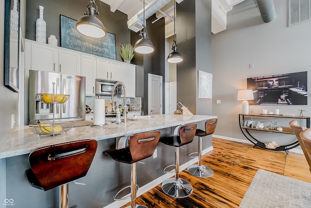 624 E Walnut St Unit 26, Indianapolis, IN 46204 - kitchen with stainless steel appliances, a high ceiling, hardwood / wood-style flooring, light stone counters, and white cabinets