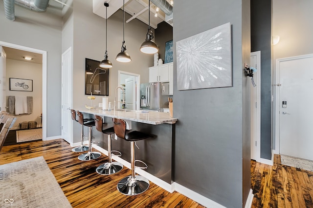 624 E Walnut St Unit 26, Indianapolis, IN 46204 - kitchen with stainless steel fridge, a high ceiling, wood finished floors, white cabinets, and beamed ceiling