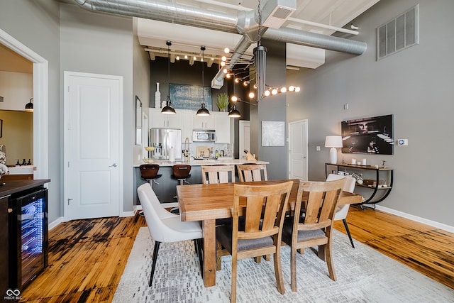 624 E Walnut St Unit 26, Indianapolis, IN 46204 - dining area featuring wine cooler, a towering ceiling, and light wood-type flooring