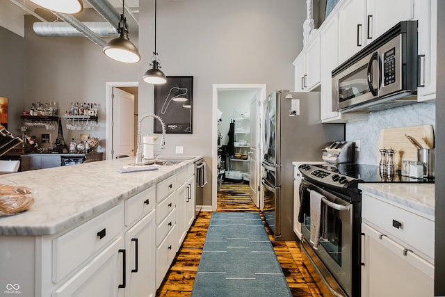 624 E Walnut St Unit 26, Indianapolis, IN 46204 - kitchen with appliances with stainless steel finishes, a towering ceiling, dark wood-type flooring, tasteful backsplash, and white cabinetry