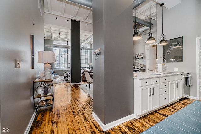 624 E Walnut St Unit 26, Indianapolis, IN 46204 - kitchen featuring wood-type flooring, white cabinetry, light stone countertops, stainless steel dishwasher, and pendant lighting