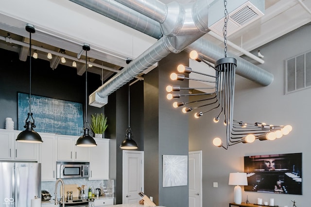 624 E Walnut St Unit 26, Indianapolis, IN 46204 - kitchen with appliances with stainless steel finishes, a high ceiling, white cabinets, pendant lighting, and backsplash