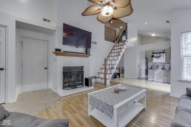 9676 Spruce Ln, Fishers, IN 46038 - living area featuring high vaulted ceiling, a fireplace, stairway, a ceiling fan, and wood finished floors