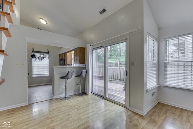 9676 Spruce Ln, Fishers, IN 46038 - kitchen with vaulted ceiling, light wood-style floors, brown cabinets, black microwave, and a peninsula