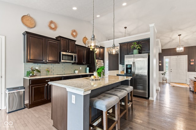 13816 Ambria Dr, Mccordsville, IN 46055 - kitchen with stainless steel appliances, dark brown cabinetry, light wood finished floors, a kitchen bar, and lofted ceiling