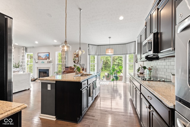 13816 Ambria Dr, Mccordsville, IN 46055 - kitchen featuring stainless steel appliances, backsplash, a center island with sink, a textured ceiling, and hardwood / wood-style flooring
