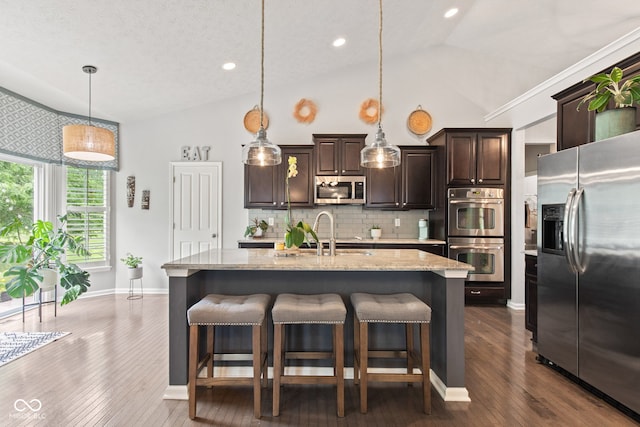 13816 Ambria Dr, Mccordsville, IN 46055 - kitchen with stainless steel appliances, dark brown cabinets, decorative backsplash, a breakfast bar, and recessed lighting
