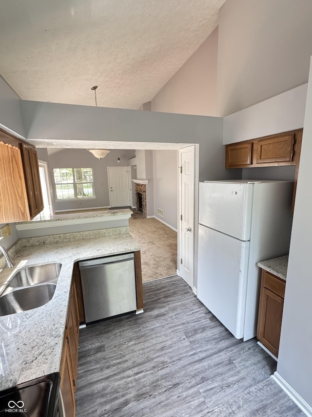 9716 Spruce Ln, Fishers, IN 46038 - kitchen featuring stainless steel dishwasher, freestanding refrigerator, a textured ceiling, brown cabinetry, and wood finished floors
