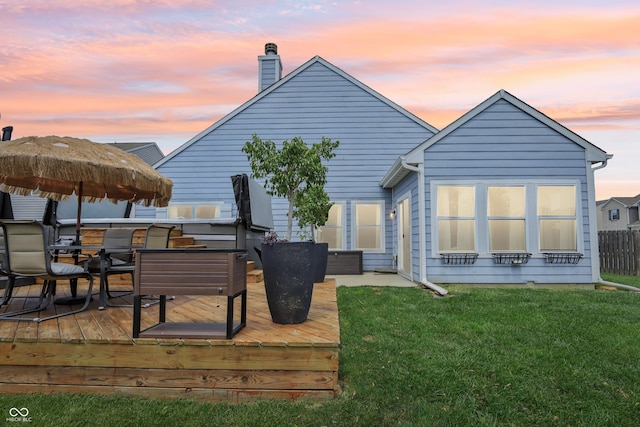 897 Sommersweet Run, Greenwood, IN 46143 - back of house at dusk featuring a wooden deck, outdoor dining area, and a chimney