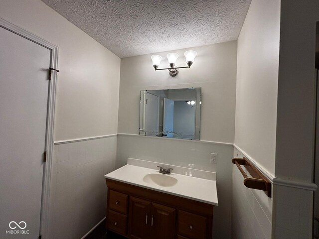 321 S Locust Dr, Morristown, IN 46161 - bathroom with vanity, a textured ceiling, a wainscoted wall, and tile walls