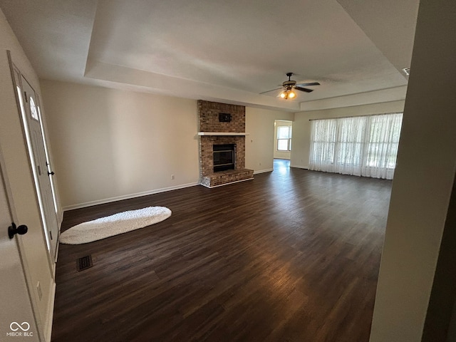 321 S Locust Dr, Morristown, IN 46161 - unfurnished living room featuring ceiling fan, dark wood-type flooring, a raised ceiling, and a fireplace