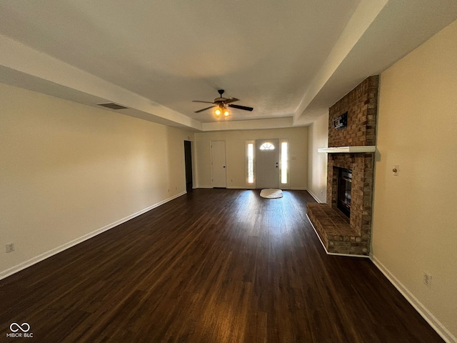 321 S Locust Dr, Morristown, IN 46161 - unfurnished living room featuring dark wood-type flooring, a fireplace, and a ceiling fan