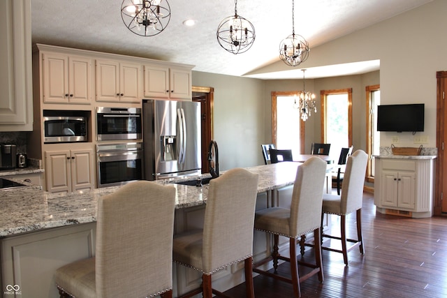 6022 S 550th Rd E, Franklin, IN 46131 - kitchen with a chandelier, lofted ceiling, appliances with stainless steel finishes, a breakfast bar area, and light stone countertops