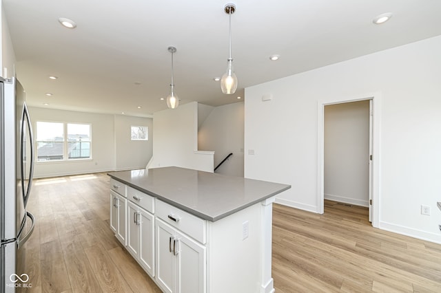 2416 Winthrop Ave, Indianapolis, IN 46205 - kitchen featuring freestanding refrigerator, dark countertops, light wood-style floors, a kitchen island, and open floor plan