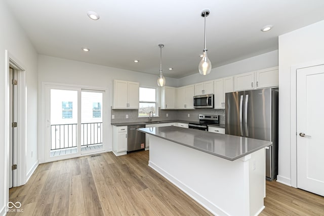 2416 Winthrop Ave, Indianapolis, IN 46205 - kitchen featuring stainless steel appliances, backsplash, white cabinets, a center island, and light wood-style flooring