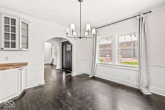 4123 N Illinois St, Indianapolis, IN 46208 - unfurnished dining area with arched walkways, a chandelier, a textured ceiling, dark wood finished floors, and a wainscoted wall