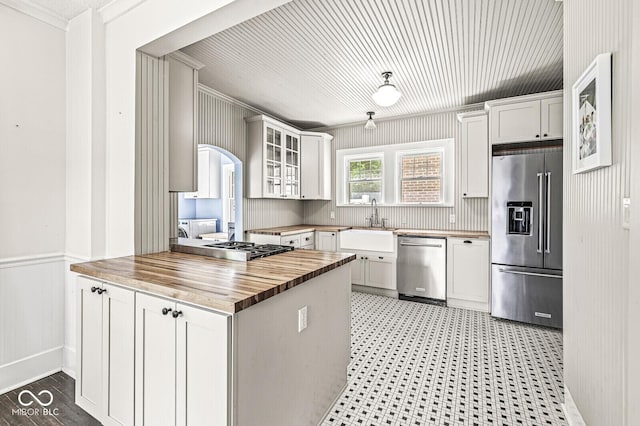 4123 N Illinois St, Indianapolis, IN 46208 - kitchen featuring stainless steel appliances, butcher block countertops, ornamental molding, glass insert cabinets, and a peninsula