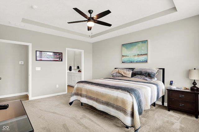 887 Tuxedo Dr, Westfield, IN 46074 - bedroom featuring a tray ceiling, light colored carpet, ensuite bathroom, and a ceiling fan