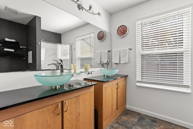 12384 Barnstone Ct, Fishers, IN 46037 - bathroom with two vanities, healthy amount of natural light, a walk in shower, and stone finish flooring