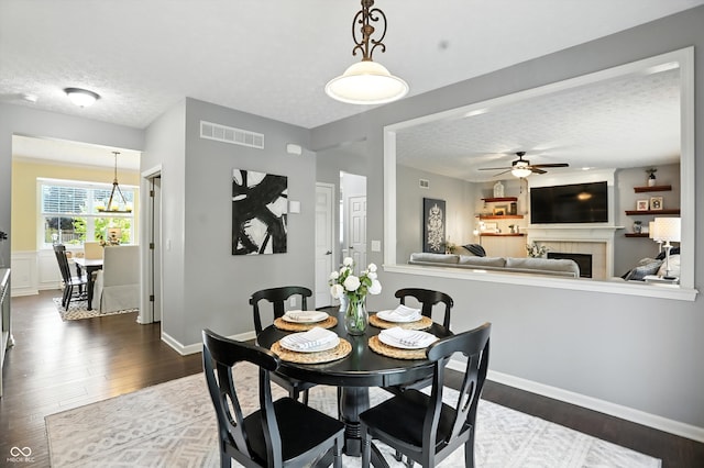 682 Shannon Ct, Noblesville, IN 46062 - dining room with a ceiling fan, dark wood-style flooring, a fireplace, and a textured ceiling