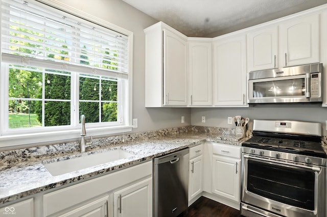682 Shannon Ct, Noblesville, IN 46062 - kitchen featuring appliances with stainless steel finishes, white cabinets, light stone counters, and dark wood-style floors