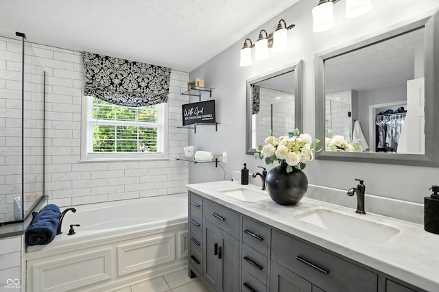 682 Shannon Ct, Noblesville, IN 46062 - bathroom featuring a garden tub, double vanity, tile patterned floors, a textured ceiling, and a spacious closet