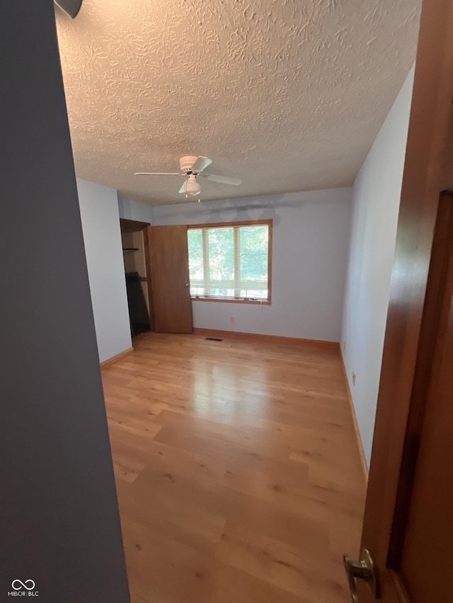 7057 Bluffwood Ct, Brownsburg, IN 46112 - empty room featuring light wood-type flooring, a textured ceiling, and ceiling fan