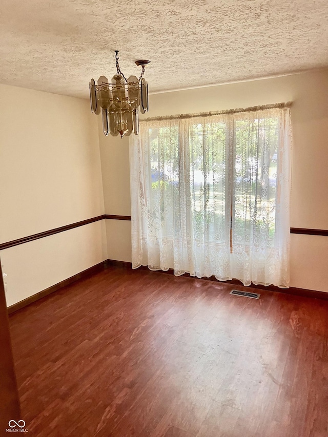 7057 Bluffwood Ct, Brownsburg, IN 46112 - empty room with a chandelier, dark wood finished floors, and a textured ceiling