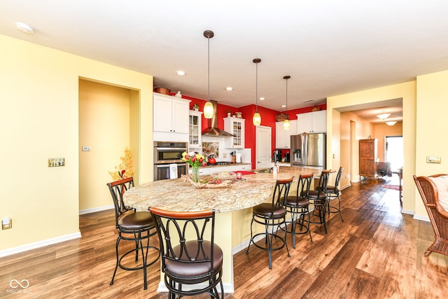 5119 Silverbell Dr, Plainfield, IN 46168 - kitchen featuring stainless steel appliances, wood finished floors, a kitchen bar, a spacious island, and white cabinetry