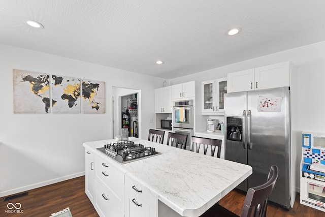 1830 Keller Ave, Columbus, IN 47201 - kitchen with appliances with stainless steel finishes, glass insert cabinets, dark wood-type flooring, a kitchen bar, and white cabinetry