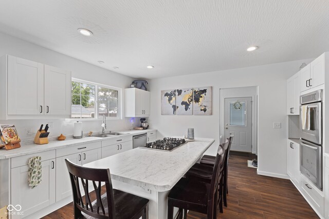 1830 Keller Ave, Columbus, IN 47201 - kitchen with appliances with stainless steel finishes, a kitchen breakfast bar, a kitchen island, dark wood-style flooring, and white cabinets