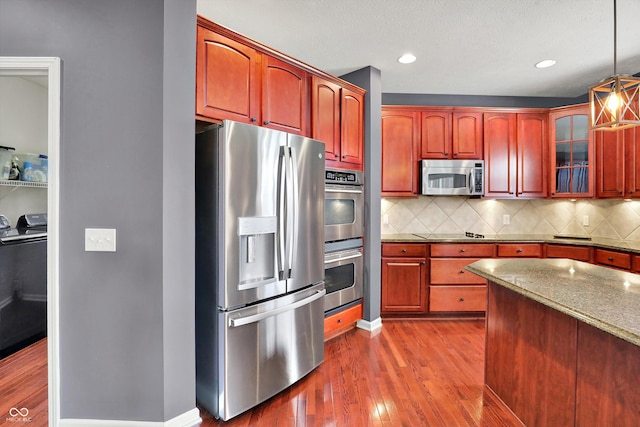 10267 Ranford Blvd, Fishers, IN 46040 - kitchen featuring stainless steel appliances, independent washer and dryer, wood finished floors, backsplash, and hanging light fixtures