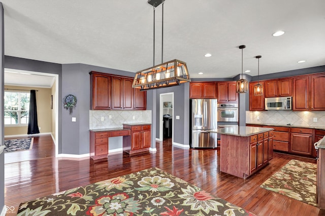 10267 Ranford Blvd, Fishers, IN 46040 - kitchen featuring appliances with stainless steel finishes, dark wood finished floors, backsplash, a kitchen island, and decorative light fixtures