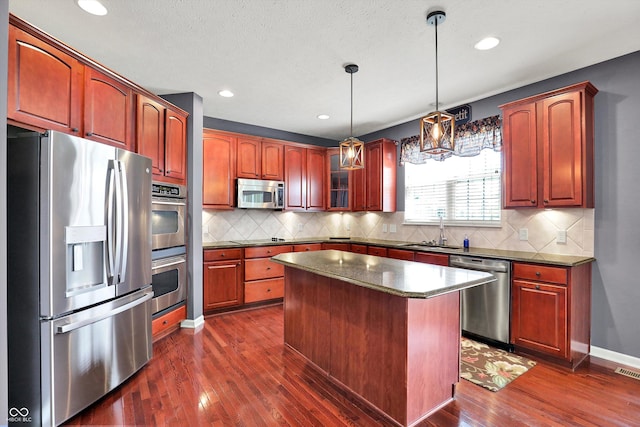 10267 Ranford Blvd, Fishers, IN 46040 - kitchen with stainless steel appliances, dark wood-style flooring, a kitchen island, decorative backsplash, and hanging light fixtures