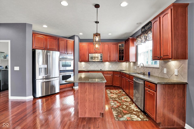 10267 Ranford Blvd, Fishers, IN 46040 - kitchen featuring appliances with stainless steel finishes, dark wood-type flooring, a kitchen island, dark stone counters, and glass insert cabinets