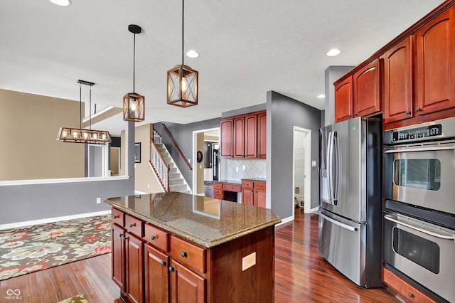 10267 Ranford Blvd, Fishers, IN 46040 - kitchen with appliances with stainless steel finishes, dark wood finished floors, a center island, dark stone counters, and pendant lighting