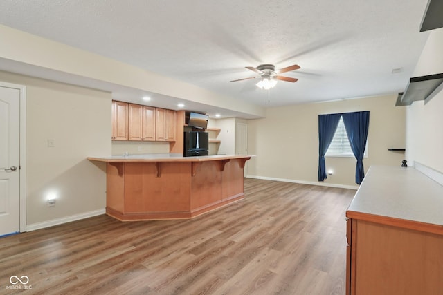 7927 Broadmead Way, Indianapolis, IN 46259 - kitchen with freestanding refrigerator, a kitchen breakfast bar, a peninsula, light countertops, and light wood-style flooring