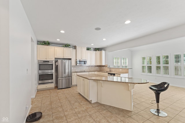2833 Holiday Way, Greenwood, IN 46143 - kitchen with stainless steel appliances, a kitchen island, a breakfast bar, backsplash, and light stone countertops