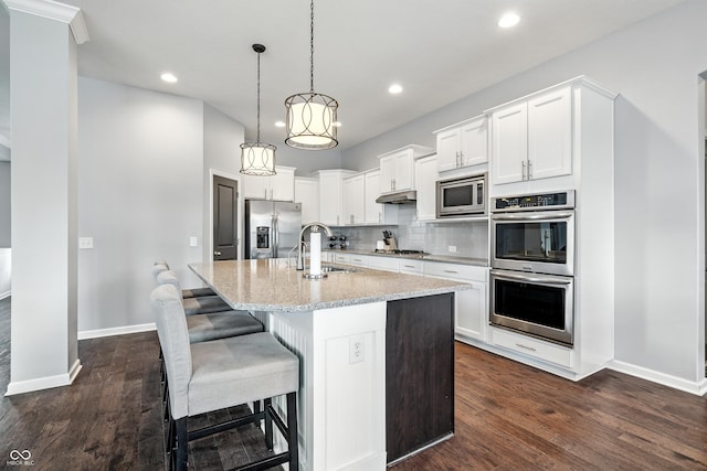 5875 Stroup Dr, Noblesville, IN 46062 - kitchen with appliances with stainless steel finishes, a center island with sink, dark wood finished floors, white cabinets, and recessed lighting