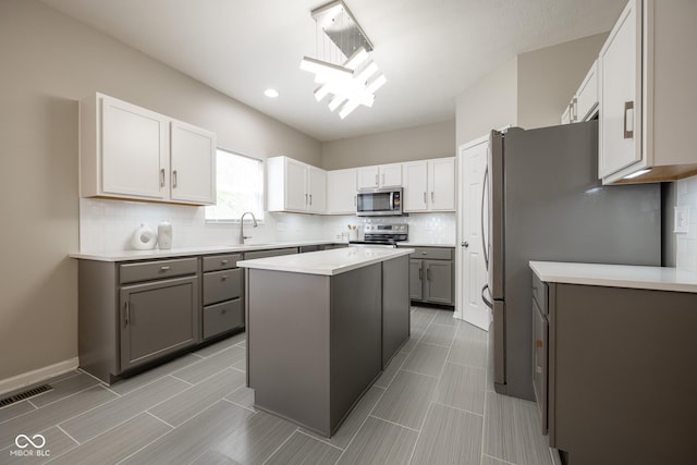 268 Larimar Dr, Whiteland, IN 46184 - kitchen with appliances with stainless steel finishes, gray cabinetry, backsplash, a center island, and light countertops