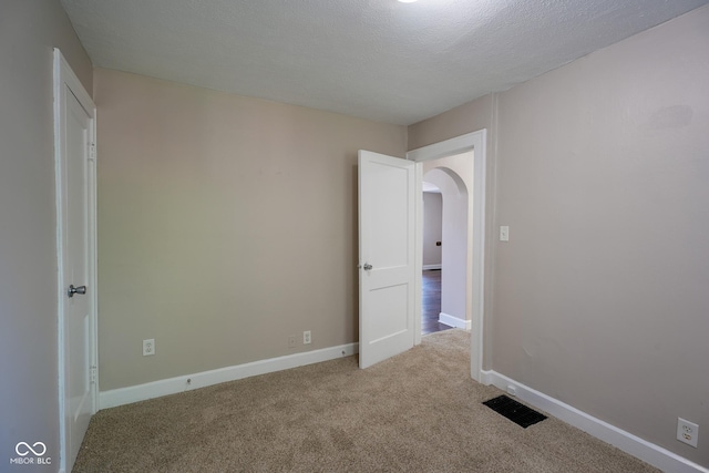 916 E 54th St, Indianapolis, IN 46220 - empty room with light colored carpet, arched walkways, and a textured ceiling