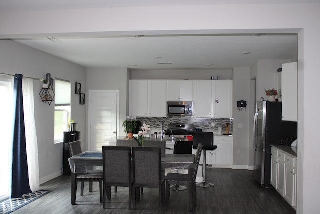 9118 Larson Dr, Pendleton, IN 46064 - kitchen with stainless steel appliances, tasteful backsplash, dark wood finished floors, white cabinets, and a center island with sink