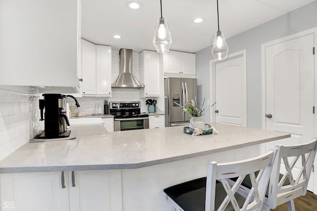 17101 Rushmore Dr, Westfield, IN 46074 - kitchen featuring stainless steel appliances, wall chimney exhaust hood, tasteful backsplash, a peninsula, and white cabinets