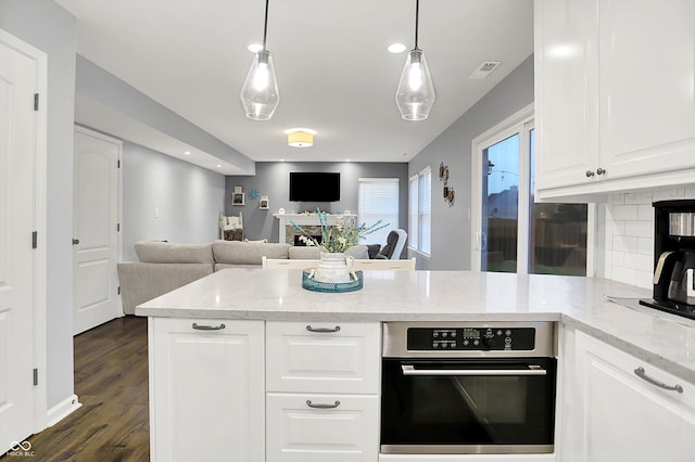 17101 Rushmore Dr, Westfield, IN 46074 - kitchen featuring oven, a peninsula, open floor plan, backsplash, and white cabinetry
