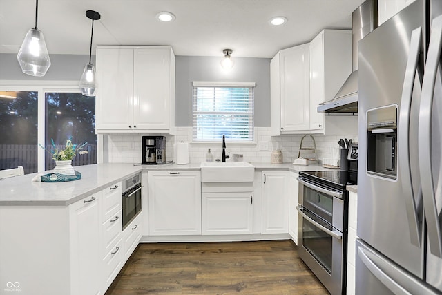 17101 Rushmore Dr, Westfield, IN 46074 - kitchen featuring appliances with stainless steel finishes, wall chimney range hood, a peninsula, dark wood-style flooring, and tasteful backsplash