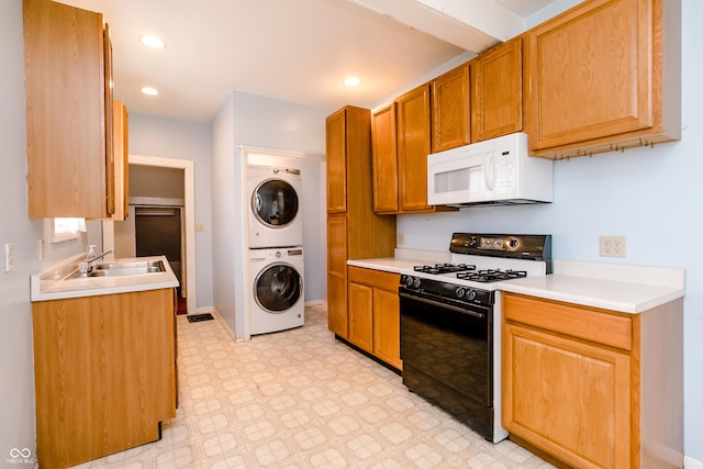 4729 Hittle Dr, Indianapolis, IN 46239 - kitchen with black gas stove, white microwave, stacked washer and clothes dryer, light floors, and light countertops